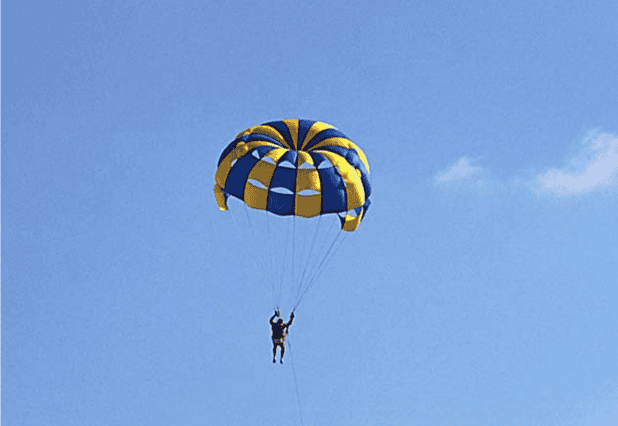 person in parachute with bright blue sky